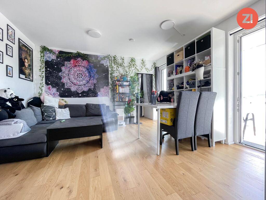 Helles Wohnzimmer mit Sofa, Schreibtisch und Zugang zum Außenbereich durch große Fenster.