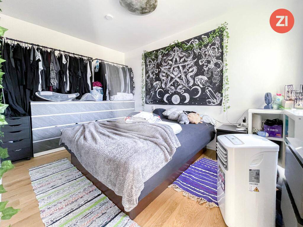 Schlafzimmer mit Holzboden, großem Bett, offenem Kleiderschrank und Klimaanlage.