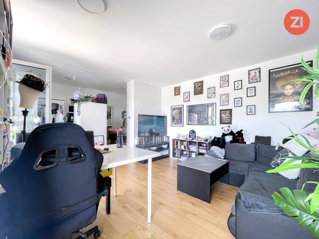 Gemütliches Wohnzimmer mit Sofa, Holzboden und einer Wand voller gerahmter Bilder.