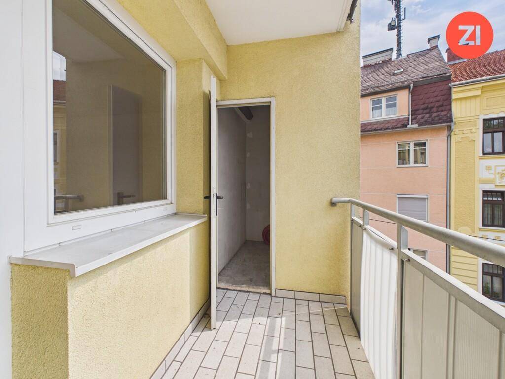 Balkon mit Zugang zu einem kleinen Abstellraum und Blick auf die Nachbargebäude.