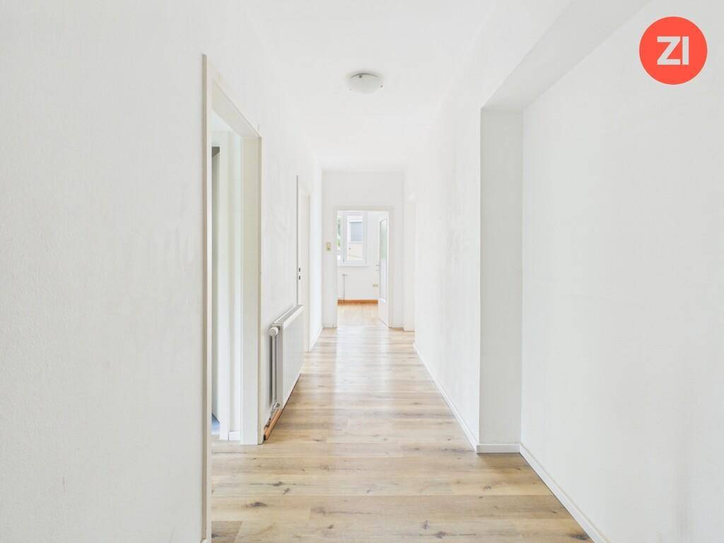 Langer, heller Flur mit Holzboden, der zu weiteren Räumen der Wohnung führt.