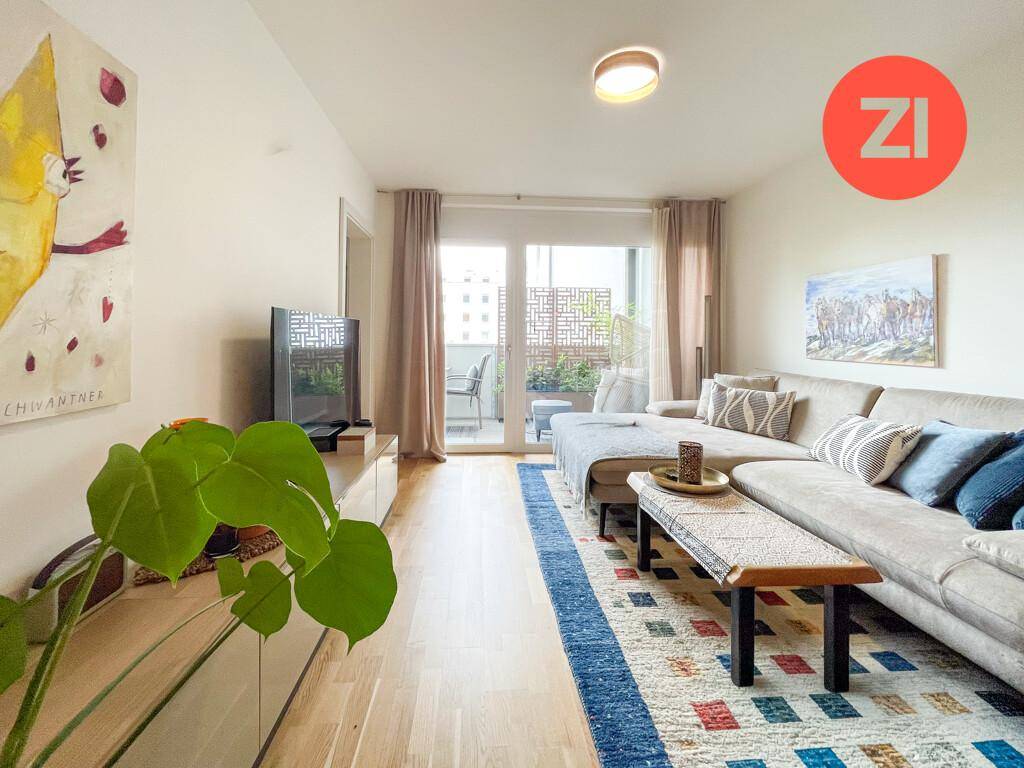 Gemütliches Wohnzimmer mit großem Ecksofa, Holzboden und direktem Balkonzugang.