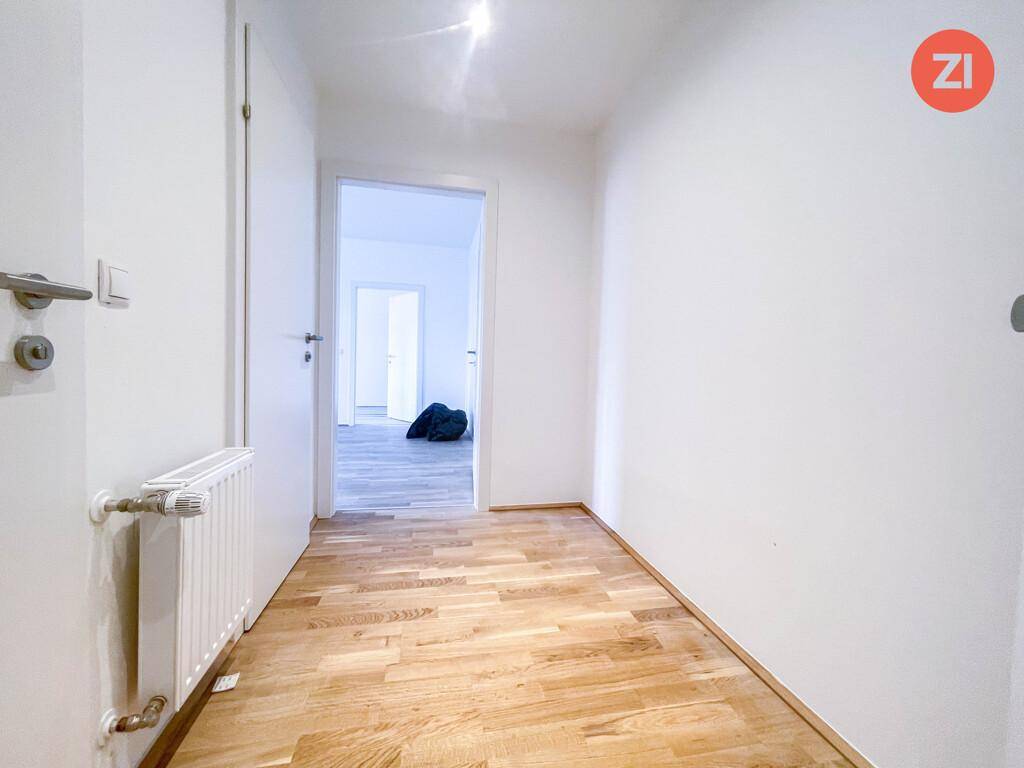 Heller Flur mit Parkettboden und Heizkörper, der zu weiteren Räumen führt.