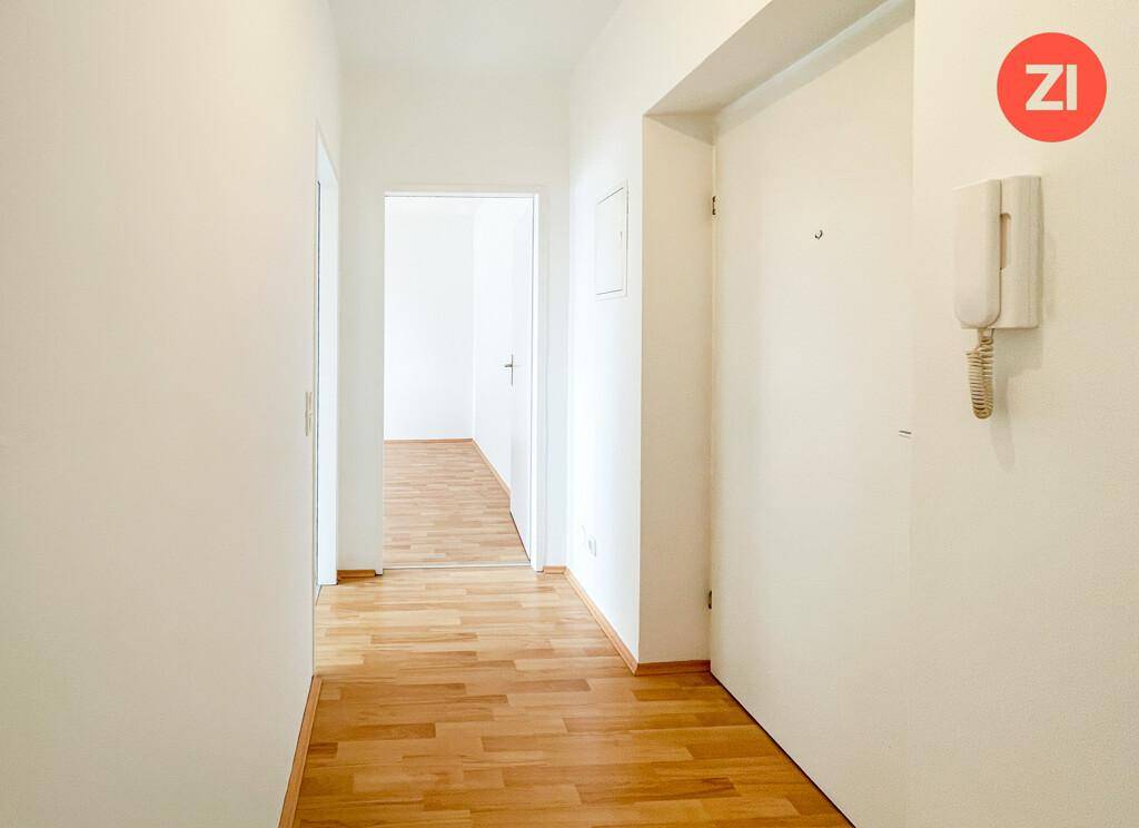 Heller Flur mit Parkettboden und mehreren Türen, ausgestattet mit einer Gegensprechanlage.