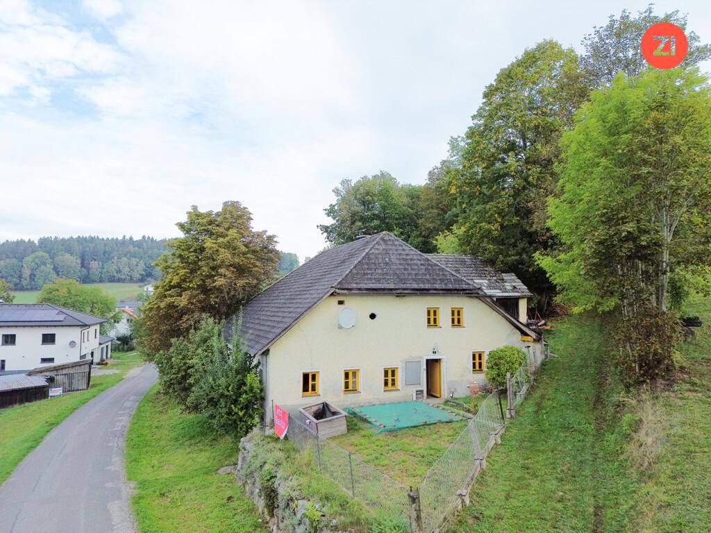 Ansicht des ländlichen Wohnhauses von der Seite mit einem kleinen Gartenbereich und viel Grün.