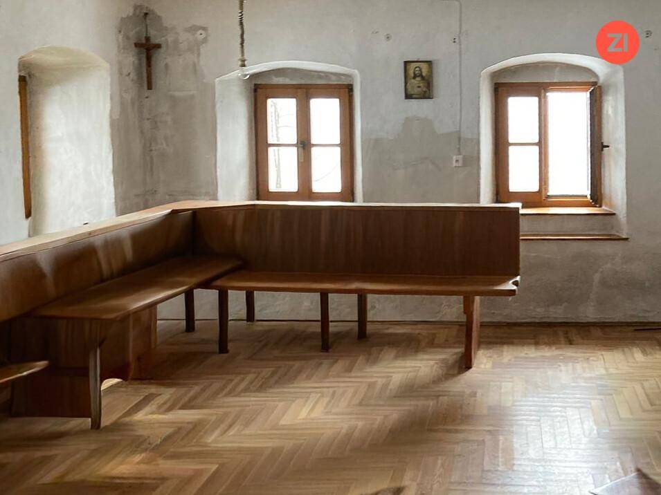 Traditioneller Wohnraum mit Holzbänken, Fischgrätparkett und kleinen Fenstern, im alpinen Stil.
