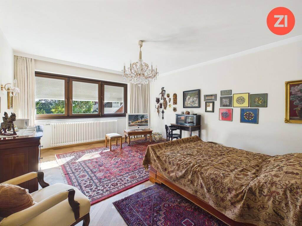 Helles Schlafzimmer mit Parkettboden, großen Fenstern und traditionellen Möbeln.