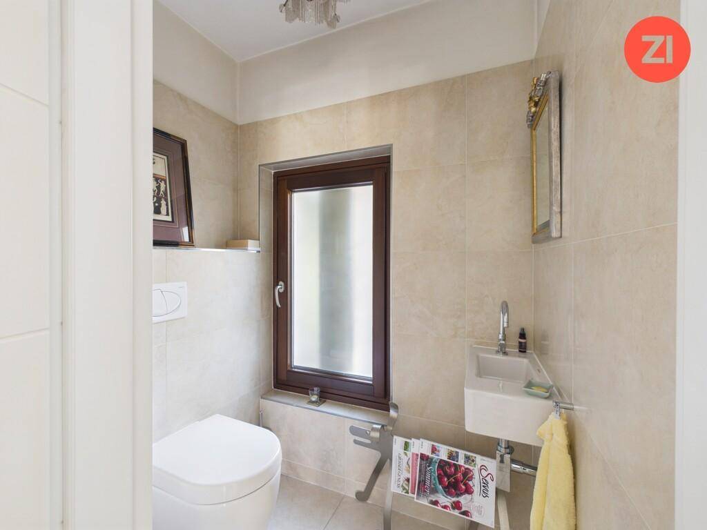 Helles Gäste-WC mit Fenster, Wand-WC und kleinem Waschbecken.