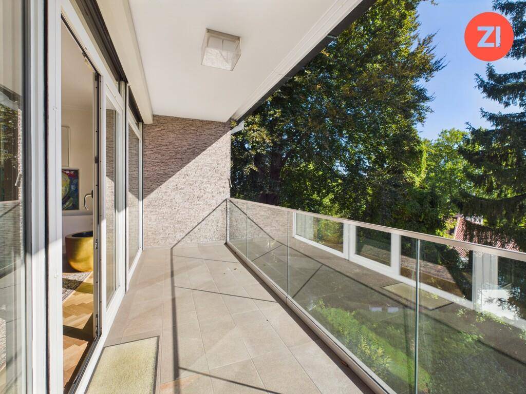 Moderner Balkon mit Glasgeländer und Blick ins Grüne, ideal zum Entspannen.