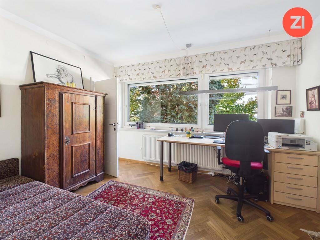 Helles Arbeitszimmer mit Schreibtisch, Parkettboden und Blick ins Grüne.