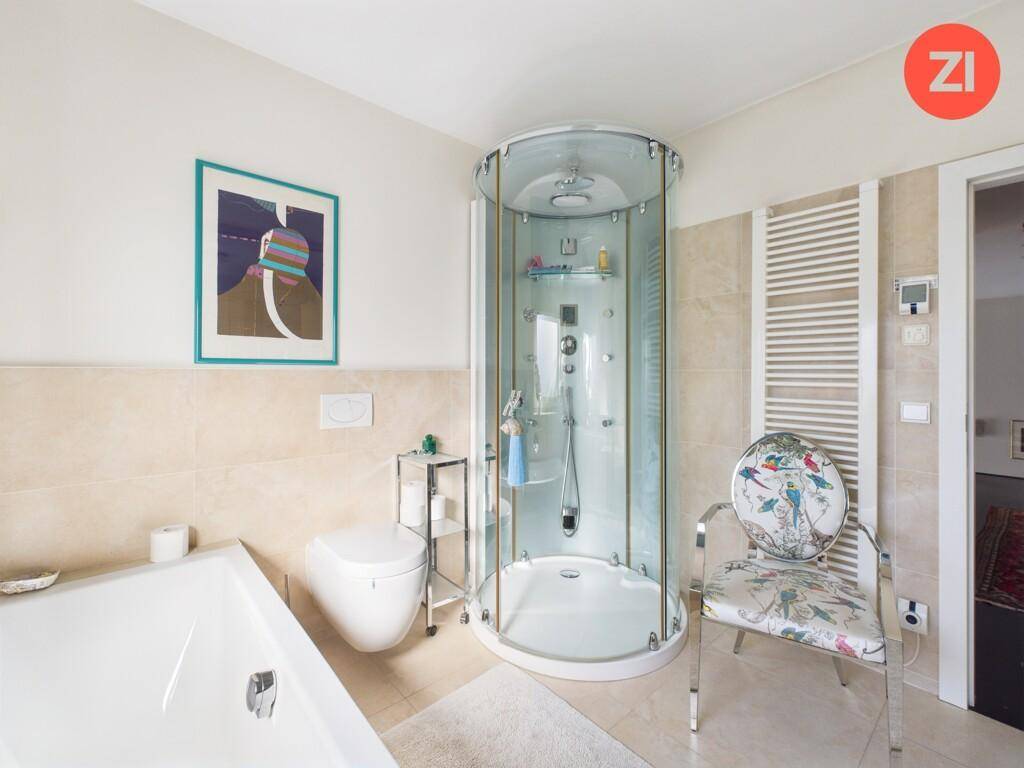 Helles Badezimmer mit Duschkabine, Badewanne und beheiztem Handtuchhalter.