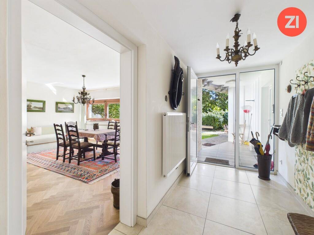 Heller Eingangsbereich mit Fliesenboden, Garderobe und Blick in den Garten.