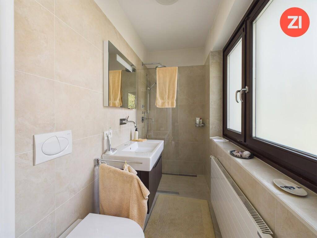 Modernes Badezimmer mit ebenerdiger Dusche, Waschbecken und Fenster.
