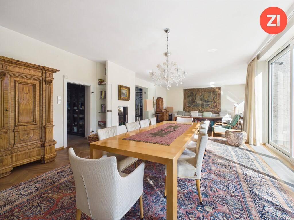 Eleganter Essbereich mit großem Holztisch, Kronleuchter und Blick ins Grüne.