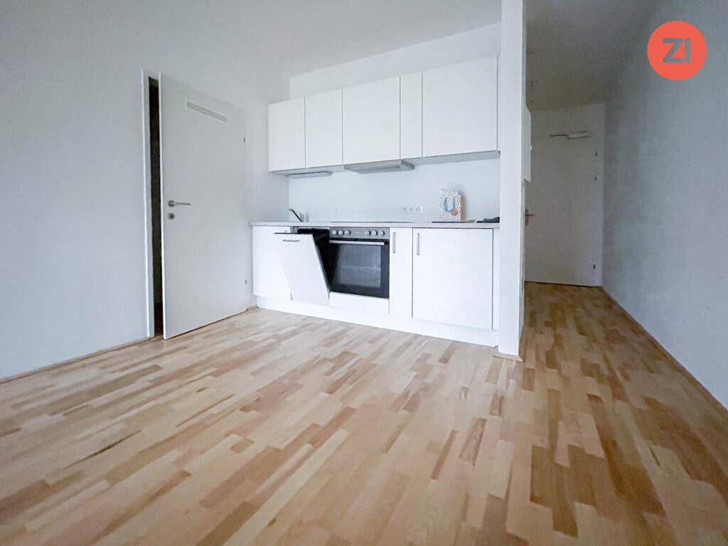 Helle Küchenzeile in offenem Wohnbereich mit integriertem Backofen und Spülmaschine.