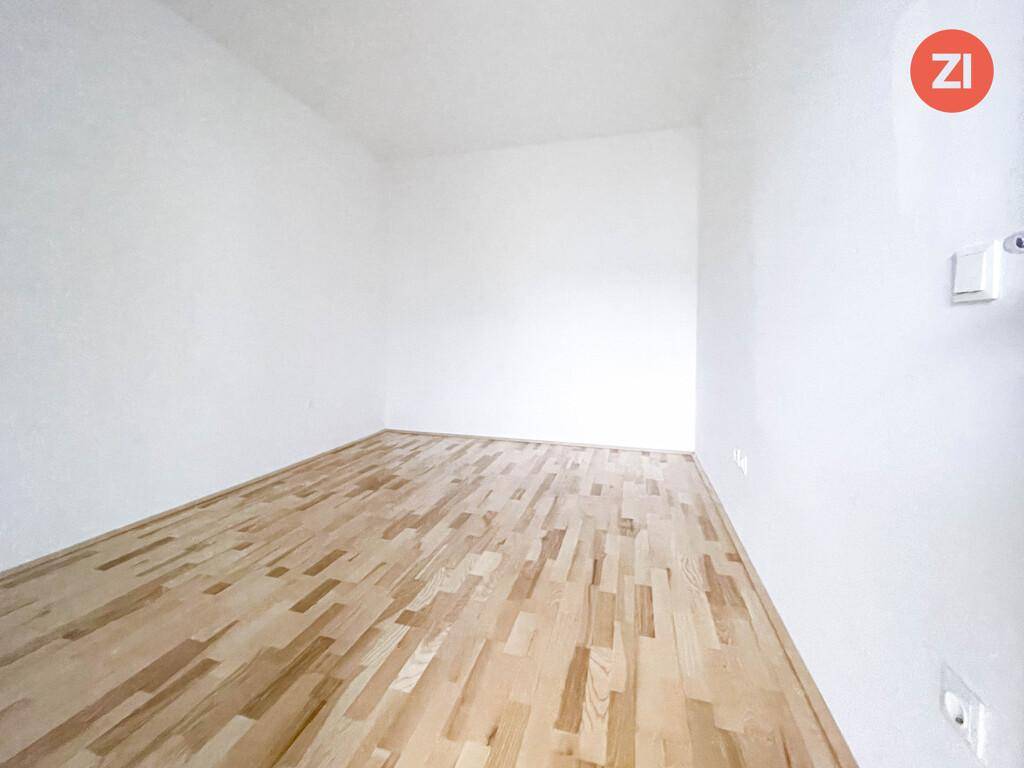 Leerer Raum mit hellen Wänden und Holzfußboden, bereit zur individuellen Gestaltung.