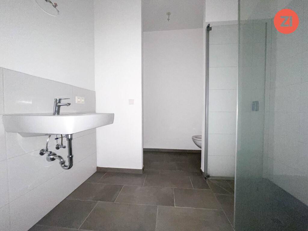 Modernes Badezimmer mit Waschtisch, Dusche und dunklen Bodenfliesen, minimalistisches Design.