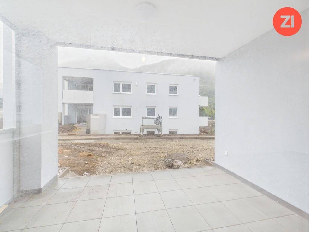 Überdachter Balkon mit Fliesenboden und Blick auf ein im Bau befindliches Gebäude.
