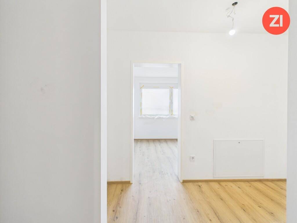 Leerer Innenraum mit hellem Laminatboden und weiß gestrichenen Wänden.