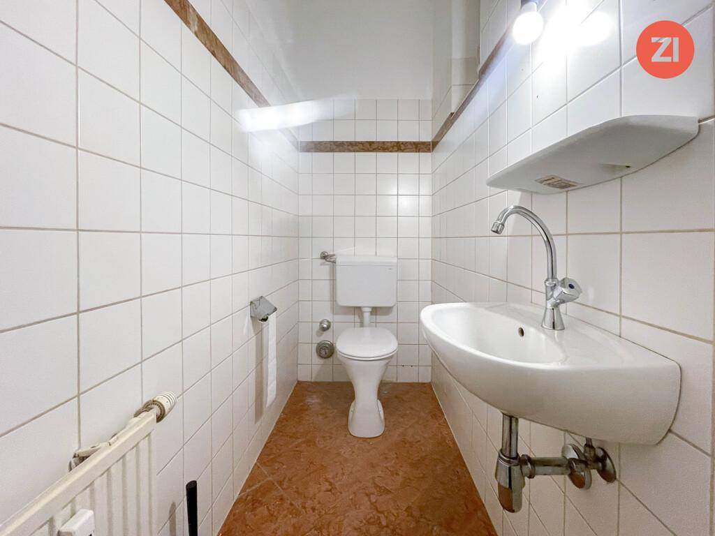 Kleines, gefliestes WC mit Toilette und Waschbecken, in einem einfachen, funktionalen Zustand.