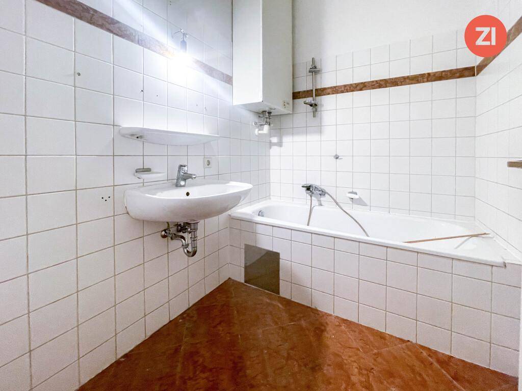Gefliestes Badezimmer mit Badewanne und Waschbecken, in einem älteren, aber gepflegten Zustand.