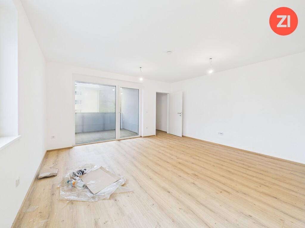 Geräumiges, helles Wohnzimmer mit Laminatboden und Schiebetür zum Außenbereich.