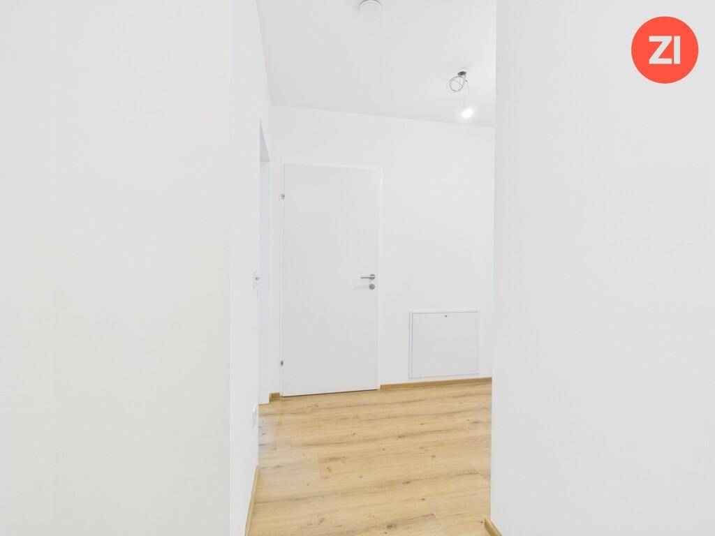 Heller, leerer Flur mit weiß gestrichenen Wänden und modernem Laminatboden.
