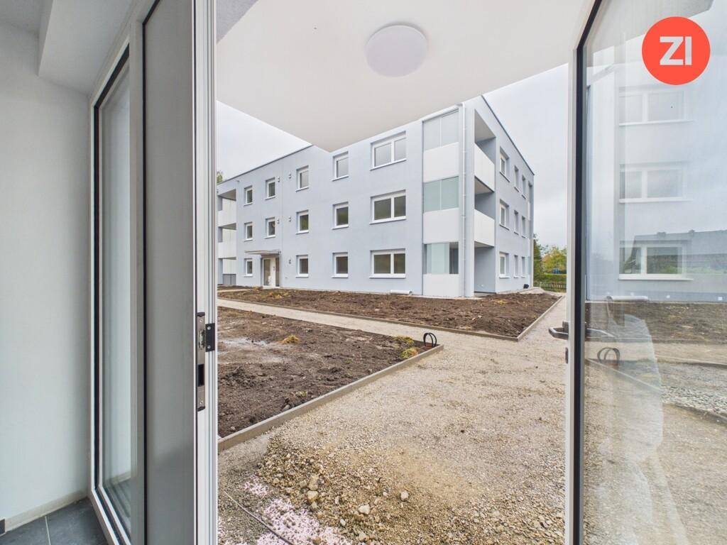 Blick von innen auf die moderne Fassade eines Neubaus mit umliegender Baustelle.