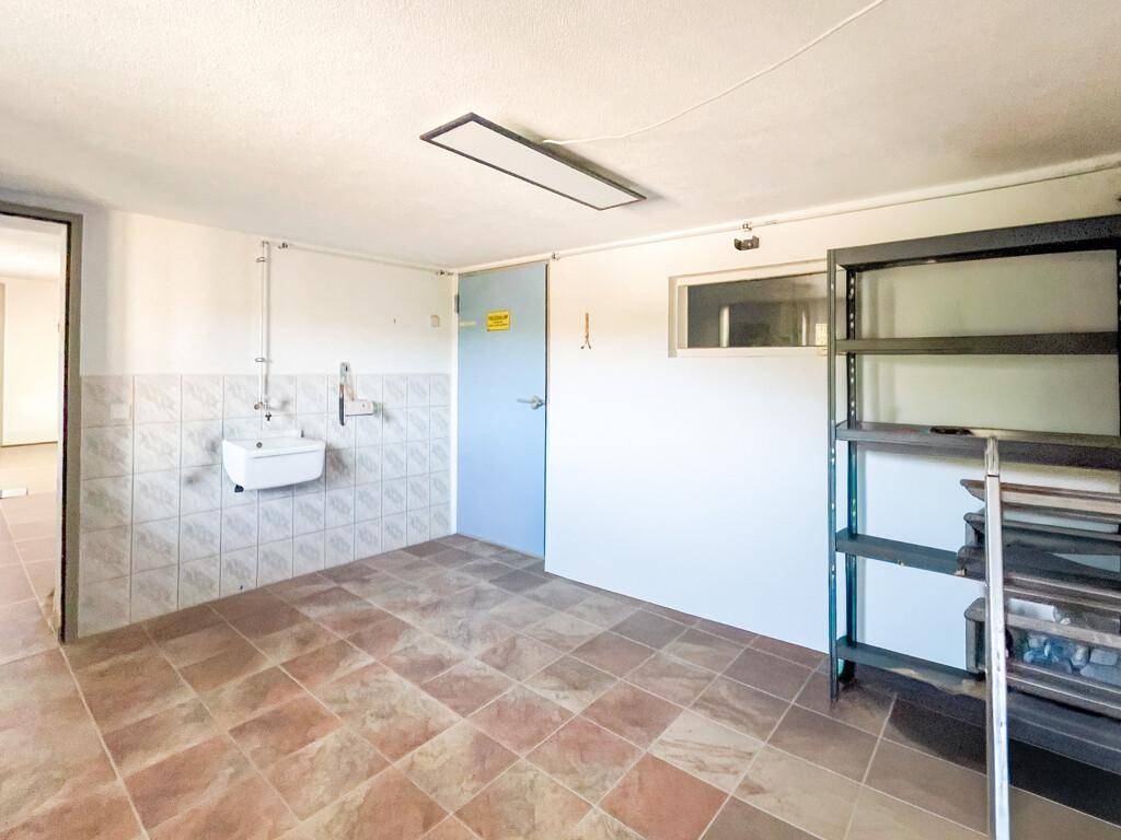 Geräumiger Hauswirtschaftsraum im Keller mit Fliesenboden und Waschbecken für praktische Nutzung.