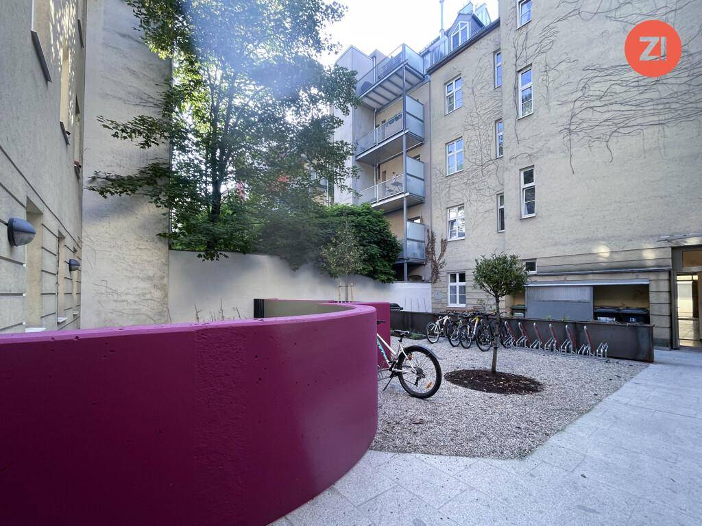 Gemeinschaftlicher Innenhof mit Fahrradständern, Bäumen und modernen, farbigen Elementen.