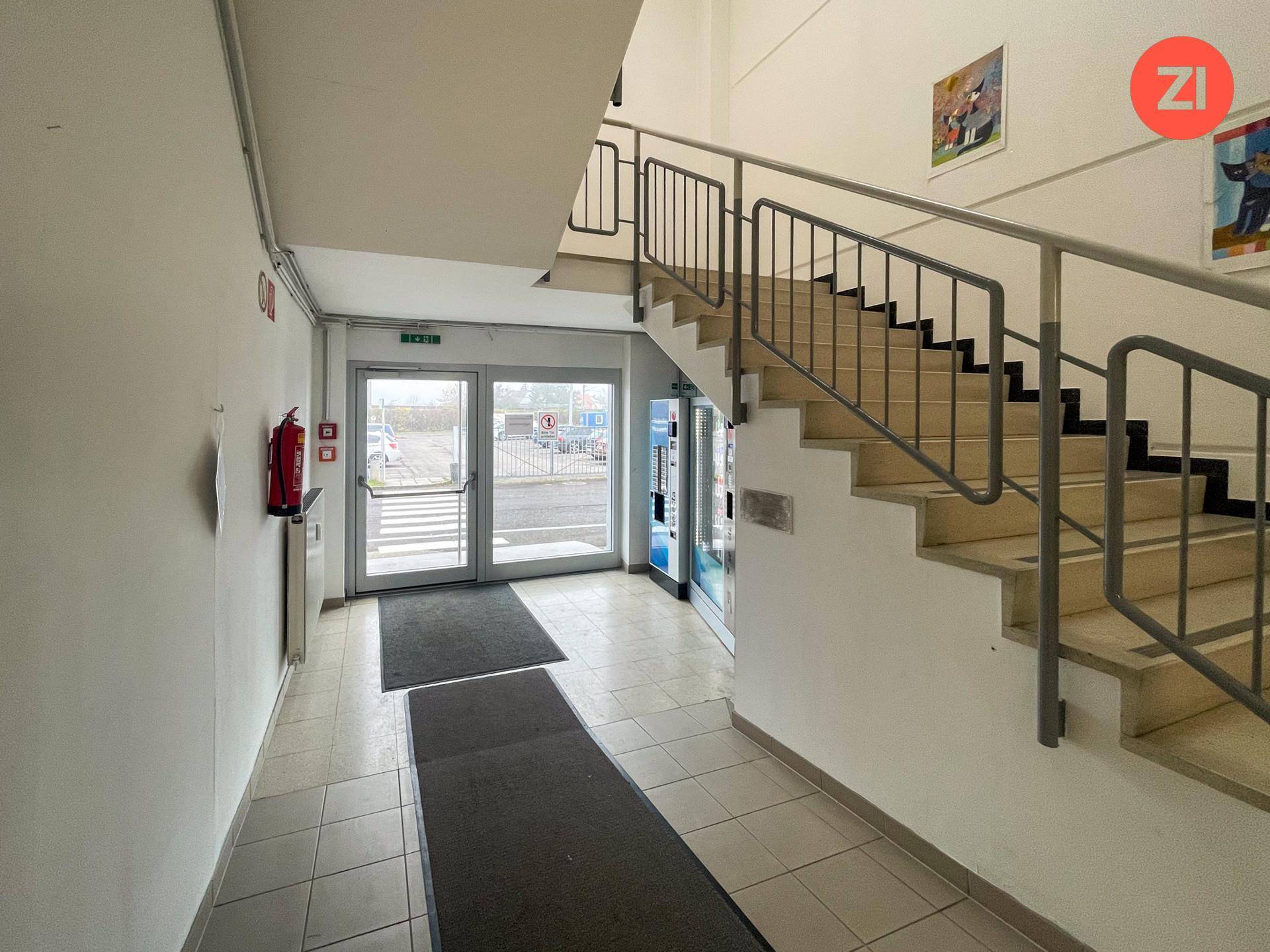 Geräumiger Eingangsbereich mit Treppe, Fliesenboden und Blick nach draußen durch die Glastüren.