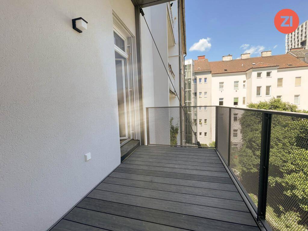 Moderner Balkon mit Holzdielenboden und Metallgeländer, bietet einen Blick auf die umliegenden Gebäude.