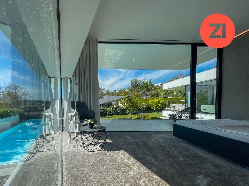 Schlafzimmer mit raumhohen Fenstern und direktem Blick auf den Pool und die grüne Umgebung.