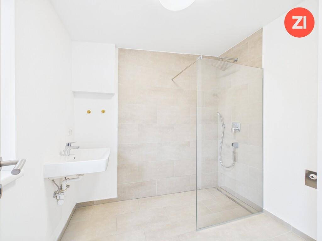 Helles Badezimmer mit ebenerdiger Dusche, modernem Waschbecken und hellen Fliesen.