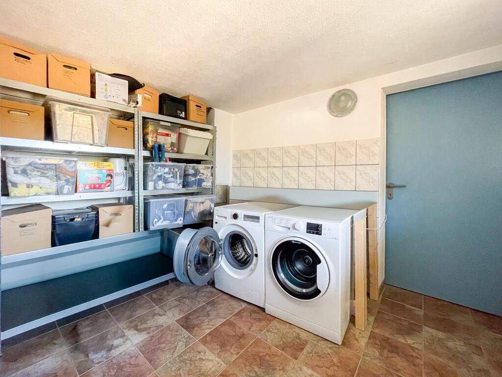 Hauswirtschaftsraum im Keller mit Waschmaschinen, Regalen und Fliesenboden für effiziente Organisation.