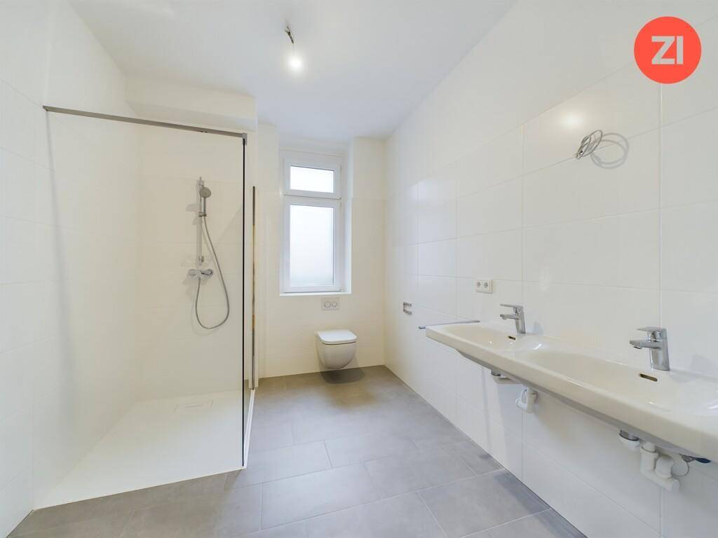 Modernes Badezimmer mit Doppelwaschbecken, großer Dusche und Fenster, hell und funktional gestaltet.