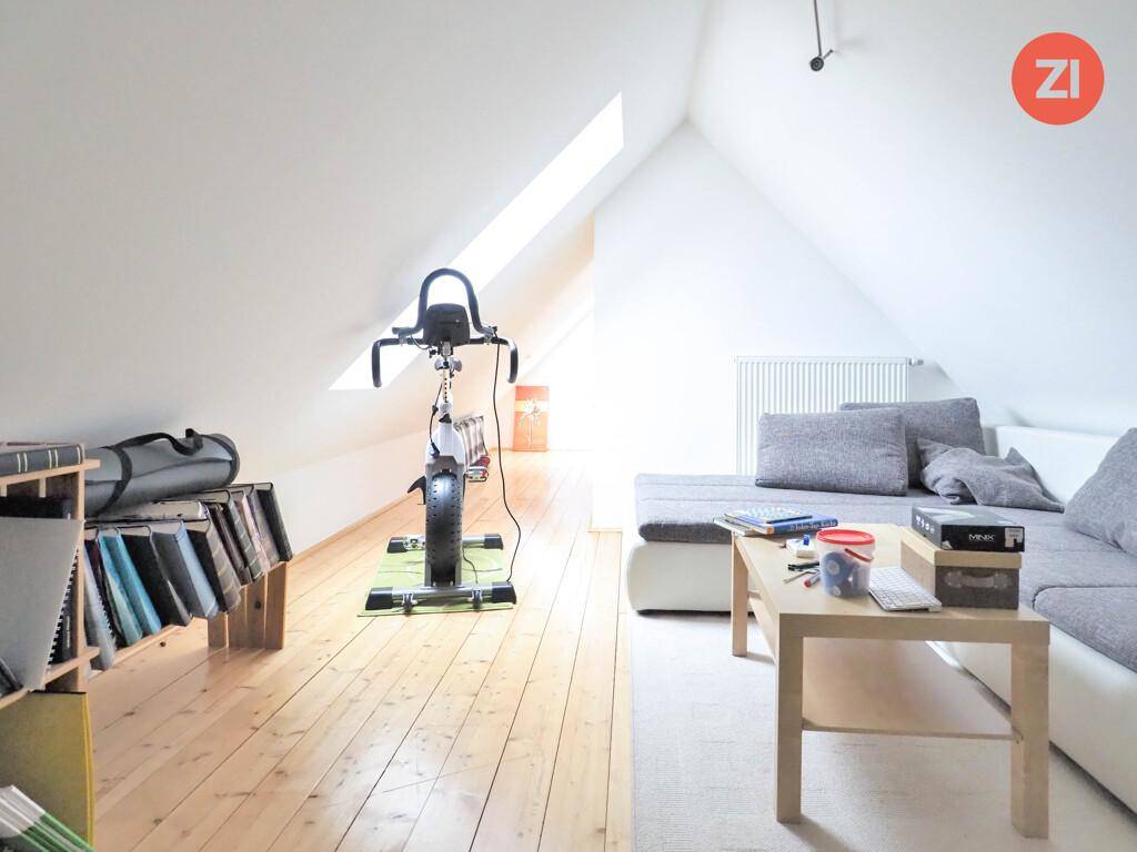Wohnbereich im Dachgeschoss mit Sofa, Couchtisch und Heimtrainer.