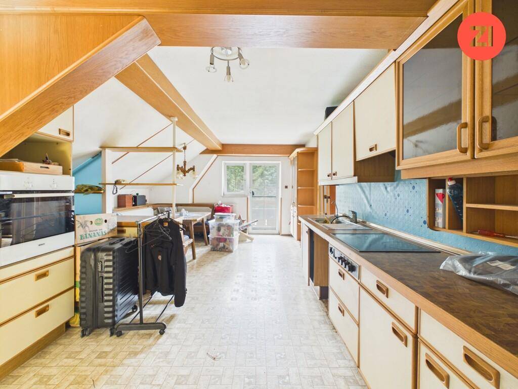 Dachgeschossküche mit Holzschränken, integrierten Geräten und Dachschrägen.