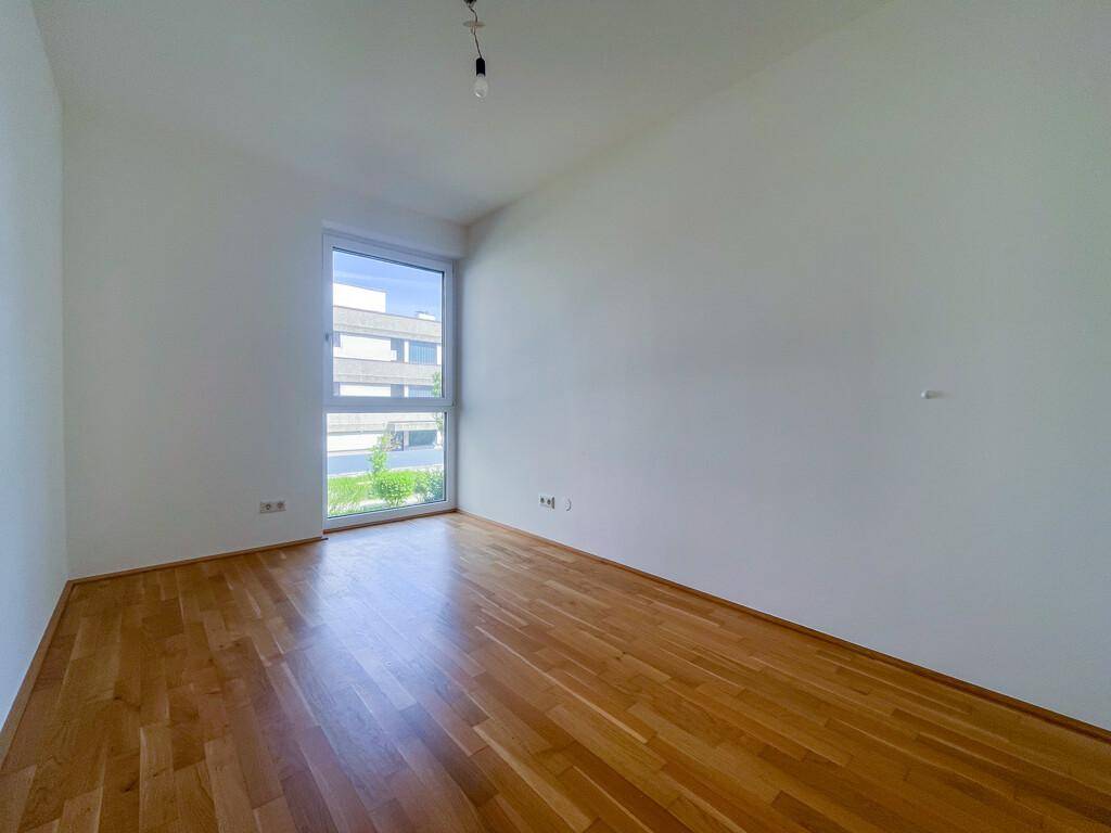 Geräumiges, helles Zimmer mit Parkettboden und großem Fenster, bereit zur individuellen Gestaltung.