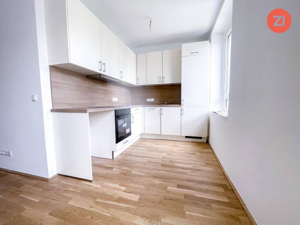 Moderne Einbauküche mit weißen Schränken, Holzarbeitsplatte und integriertem Backofen in hellem Raum.
