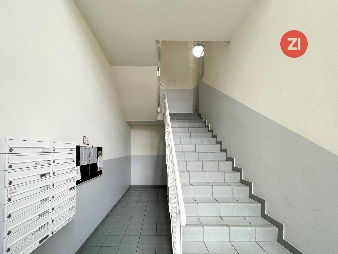 Treppenhaus mit Fliesenboden, Briefkästen und schlichtem Design im Gemeinschaftsbereich.