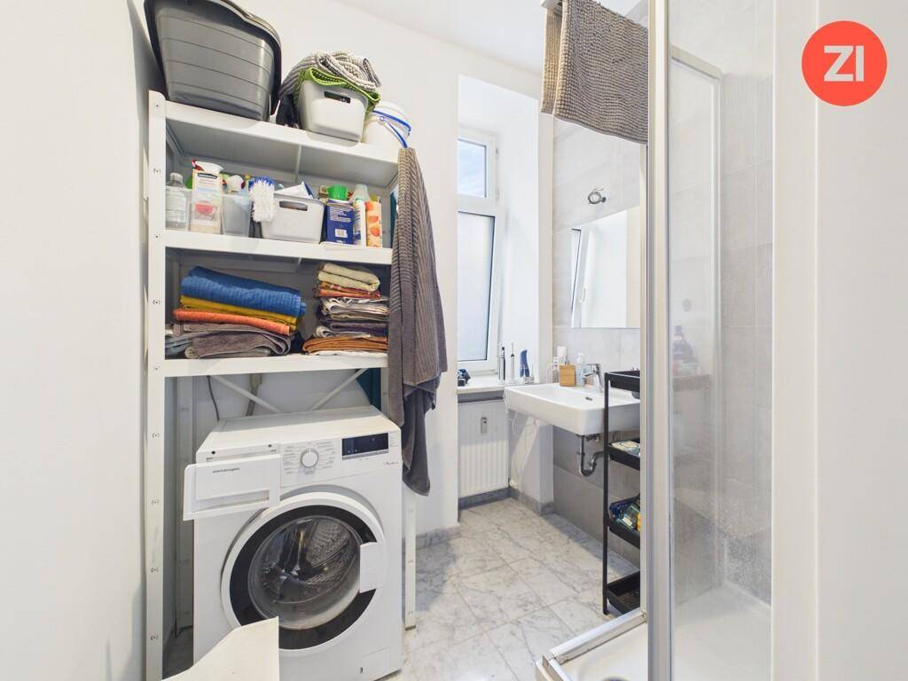 Badezimmer mit Waschmaschine, Regalen für Handtücher und einem Waschbecken.