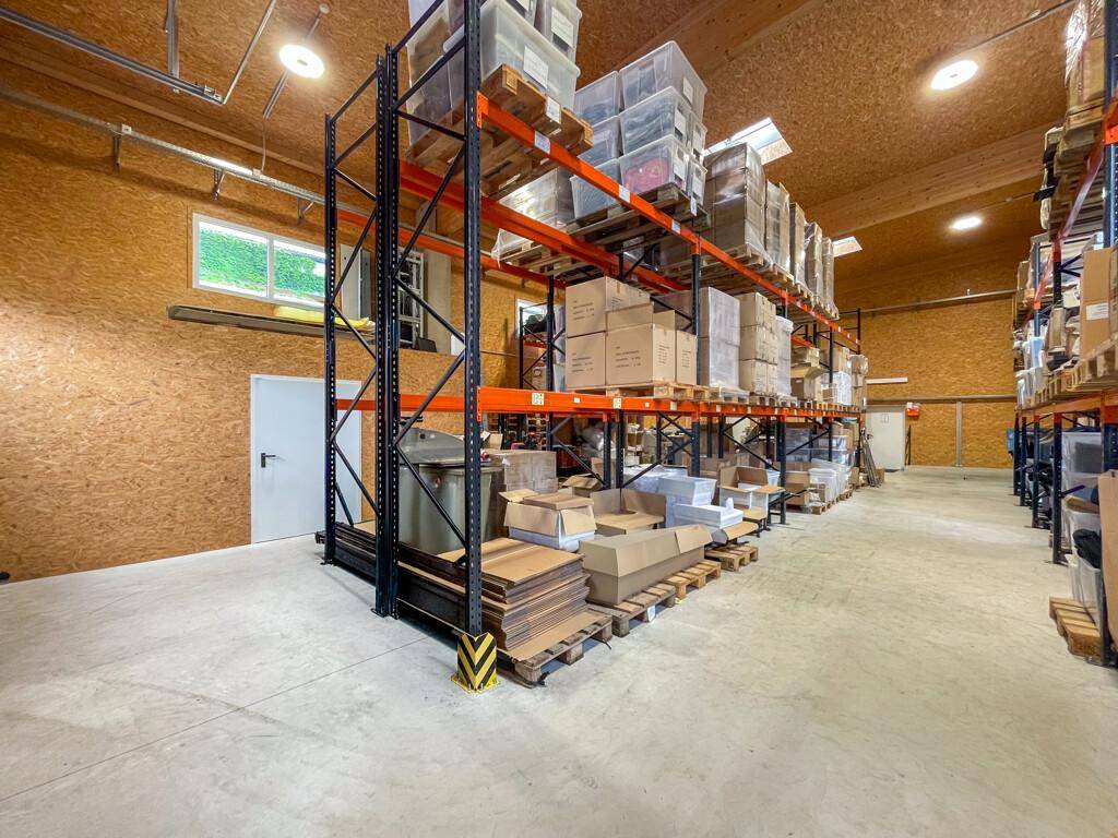 Geräumige Lagerhalle mit hohen Regalen voller Kartons, Betonboden und sichtbarer Holzdecke.