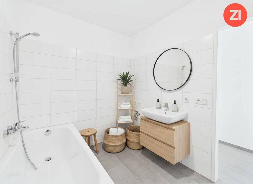 Modernes Badezimmer mit Badewanne, Dusche, Einzelwaschbecken und weißen Wandfliesen.