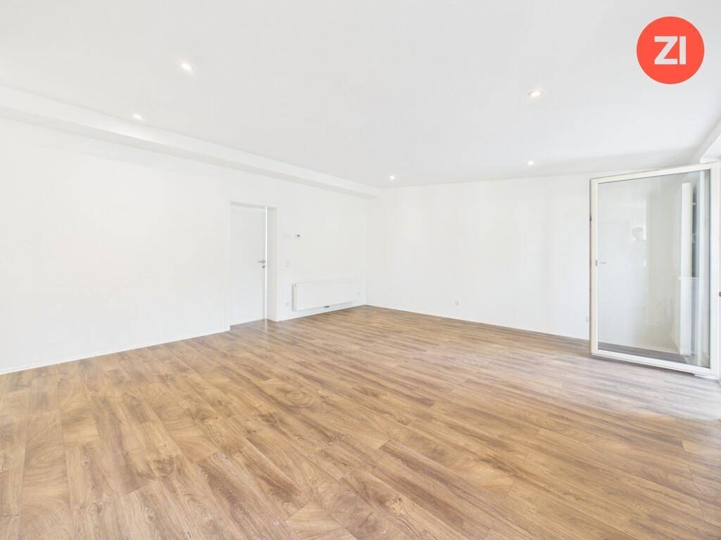 Heller, unmöblierter Raum mit Laminatboden und Zugang zu einem Balkon, vielseitig nutzbar.