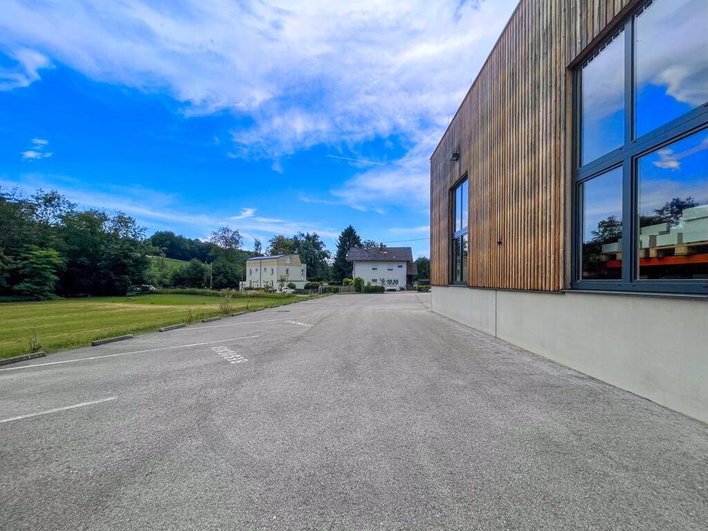 Ansicht der modernen Holzfassade des Gebäudes mit großen Fenstern und einem weitläufigen Parkplatz davor.