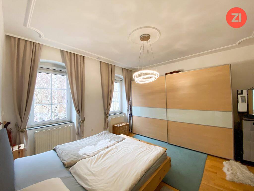 Helles Schlafzimmer mit Doppelbett, großem Einbauschrank und zwei Fenstern, die viel Licht hereinlassen.