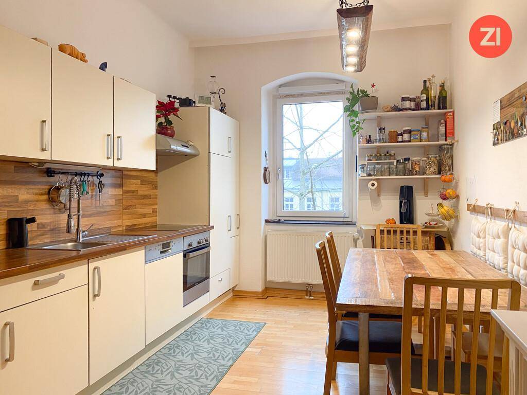 Gemütliche Wohnküche mit Holztisch, weißen Schränken und Fensterblick, ideal für gemeinsame Mahlzeiten.