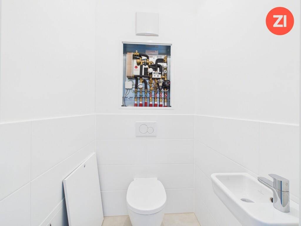 Funktionale Gästetoilette mit wandhängendem WC, kleinem Waschbecken und Heizungsverteiler.