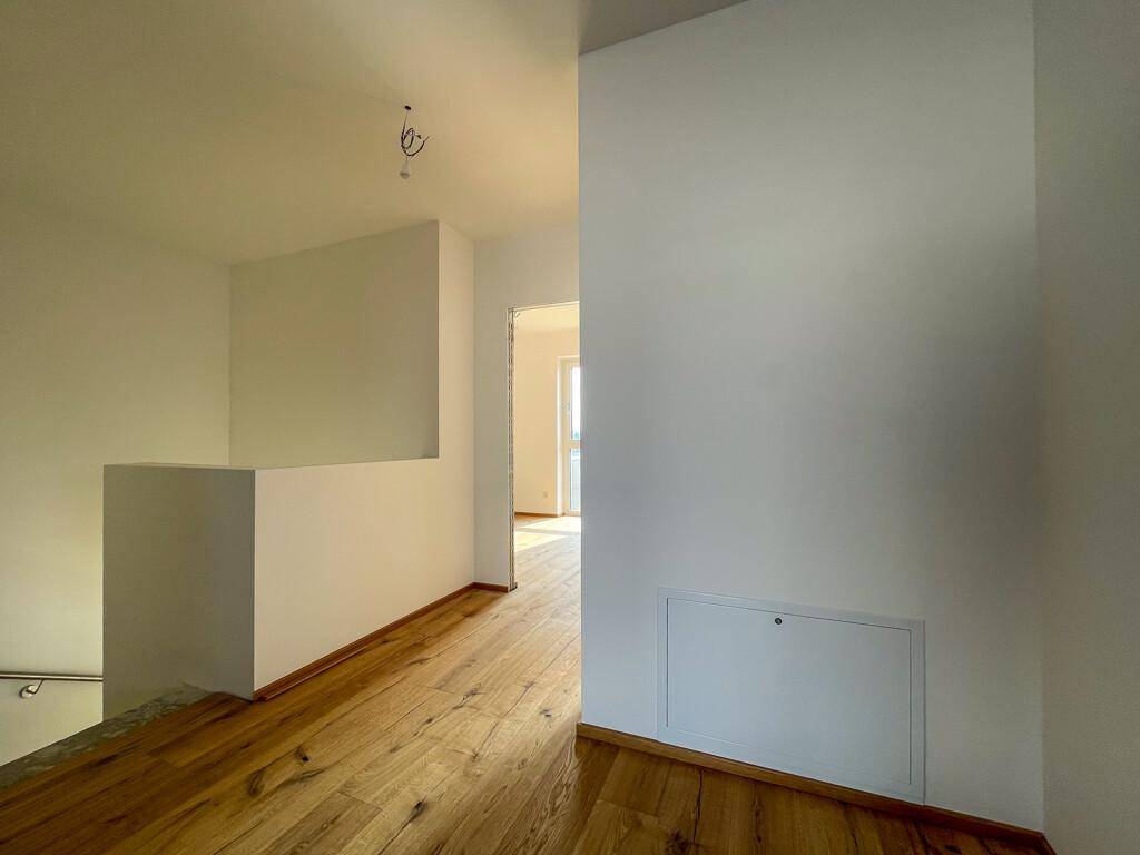 Geräumiger Flur im Obergeschoss mit Holzboden und Blick auf den Treppenaufgang.